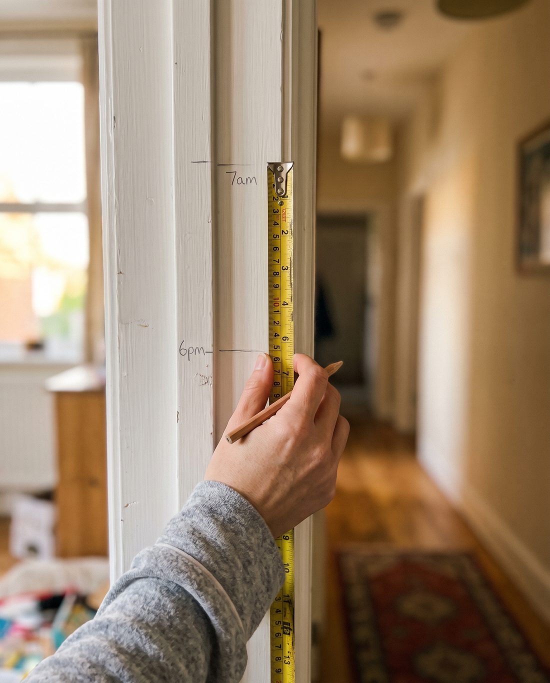 Pencil height marks on a door frame at 7am and 6pm, with the 6pm mark lower